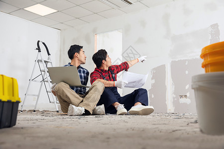 建筑平面图装修工人坐在地上拿着笔记本电脑讨论施工方案背景