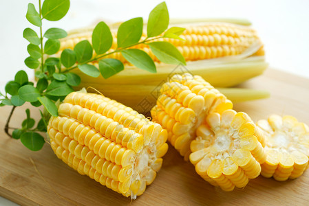 一串玉米切开的玉米放在菜板上面背景