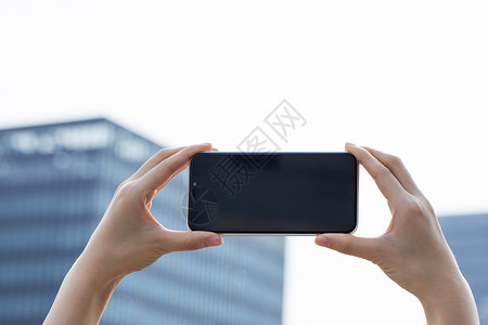 女性拿手机拍远处建筑特写图片素材