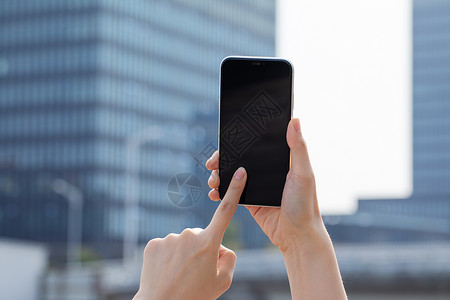 女性拿手机拍远处建筑特写背景图片