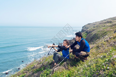 坐在海边山坡上远望男女图片