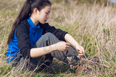 草地上系鞋带女生图片