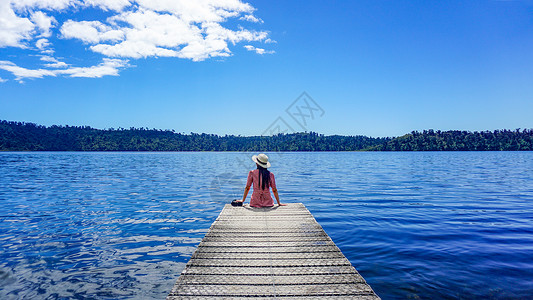 坐在湖边的女孩儿湖边木栈道女孩背影旅行度假背景