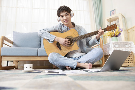 弹吉他男孩坐姿在家练习吉他的青年男性背景