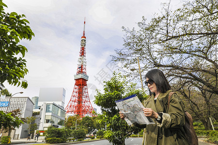 地图地标站在东京塔前看旅游地图的旅行者背景