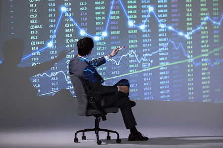 坐椅子的人商务男性坐椅子上分析股市图背景