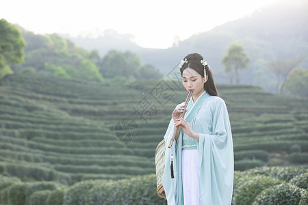 汉服古装美女在茶园里吹竹笛背景图片