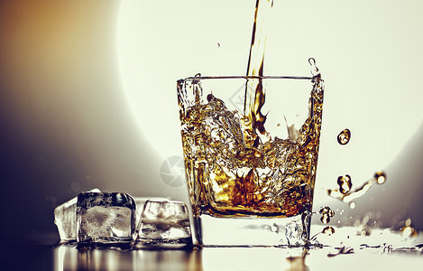倒入加冰块的酒杯中溅起酒花的XO酒背景图片