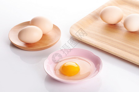鸡蛋黄盛放在托盘上的鸡蛋和盛放在盘子里的蛋黄蛋清背景