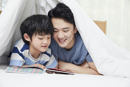 父子阅读年轻爸爸陪儿子一起看书背景