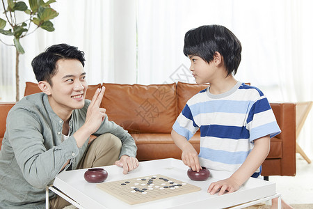 年轻爸爸和孩子下五子棋背景图片