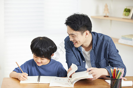 年轻爸爸辅导儿子写作业背景图片