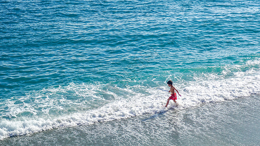 海水浪花素材海边玩耍的小男孩背景