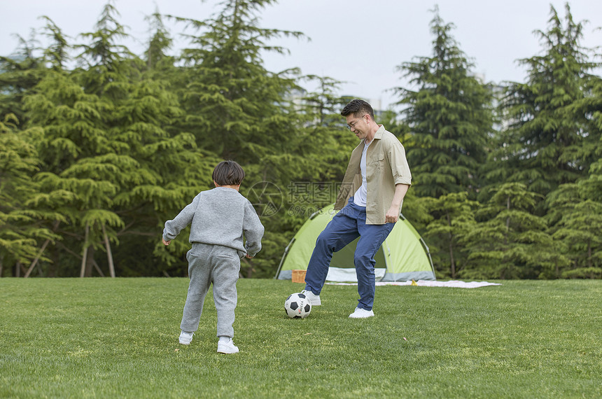 草坪上踢足球的父子图片