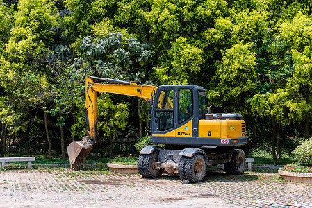 作业车停在树荫的挖掘机背景