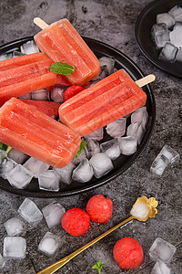 甘甜的草莓西瓜味的冰棒放置在冰块上背景