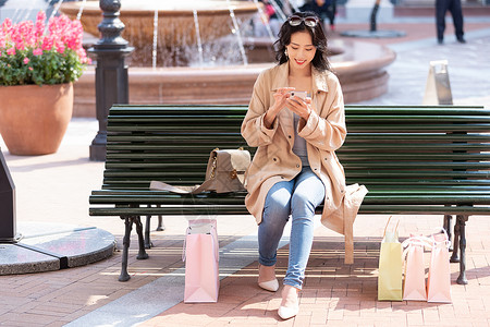 青年美女逛街购物展示手机青年女性坐在椅子上休息玩手机背景