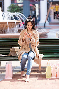 青年女性坐在椅子上休息玩手机图片