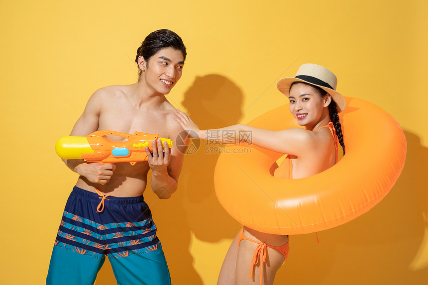 夏日泳装情侣拿着水枪和游泳圈图片