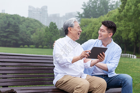 中老年父子公园长椅上看平板图片