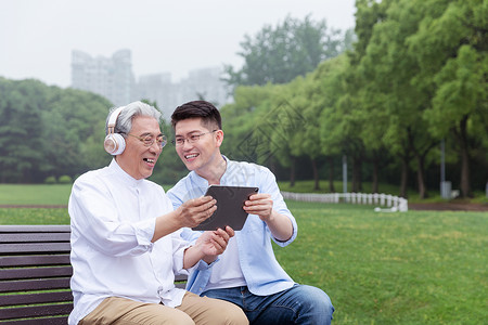 中老年父子公园长椅上听音乐高清图片