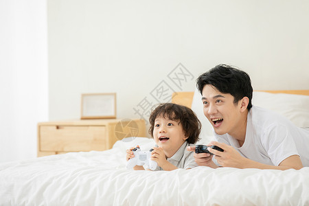 父子居家床上玩电子游戏背景图片