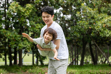 抱着锦鲤的男孩爸爸抱着儿子公园里嬉戏背景