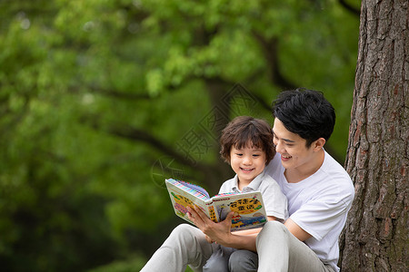 公园里的人父子在公园里看童话故事书背景