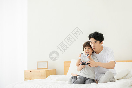 亲子特惠游传单爸爸抱着儿子在床上打电子游戏背景