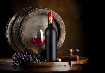 胶桶放在酒窖橡木桶前的红酒和盛有红酒的红酒杯背景