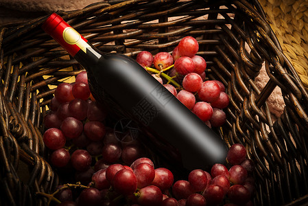 放在藤编篮子里的红酒瓶和酿酒葡萄背景图片
