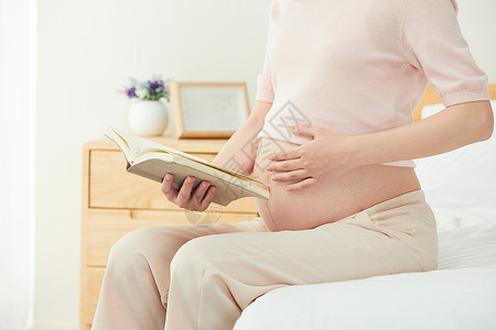 蓝色读书母亲节孕妇坐在床边阅读背景