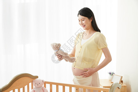 孕妇拿着玩偶微笑图片