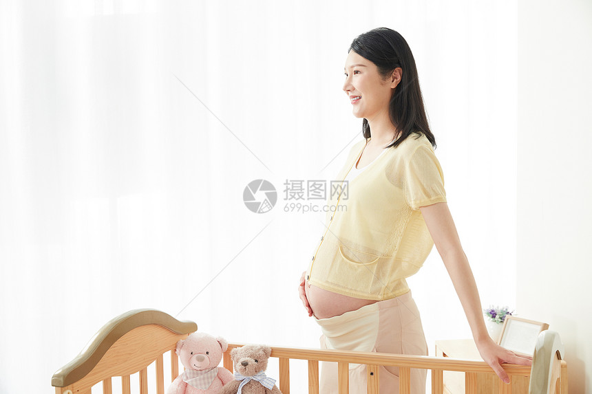 孕妇站在婴儿床旁图片