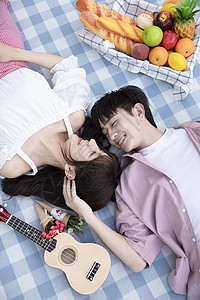 青年情侣躺在野餐垫上图片