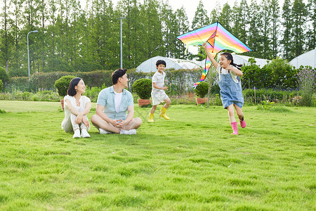 活动激励年轻夫妻看着孩子追逐玩风筝背景