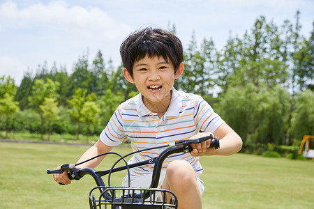 小男孩草坪上骑单车高清图片