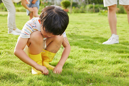 小男孩蹲在草坪上低头生闷气背景图片
