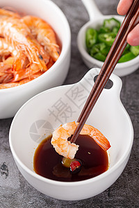 筷子夹起虾仁沾酱汁背景图片