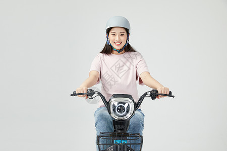 青年女性戴头盔骑电动车高清图片