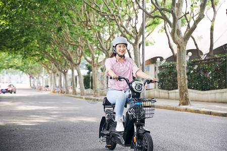 骑行头盔美女骑电动车低碳出行背景
