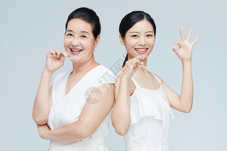 老年人一起拍照中年女性和年轻美女一起拿牙套展示背景