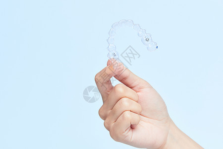 隐形矫治器女性手拿牙套展示特写背景