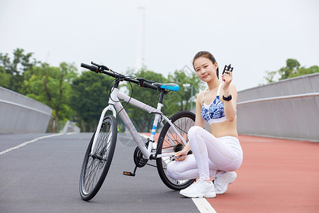 骑行美女公园里修理自行车背景图片