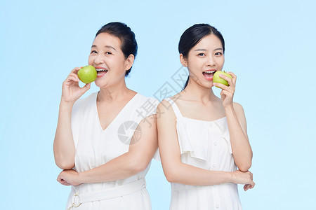 吃嘴巴老年女性和年轻美女吃苹果背景