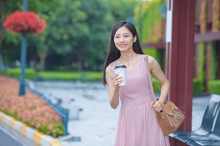 等待公交车的青年女性手捧咖啡杯背景图片