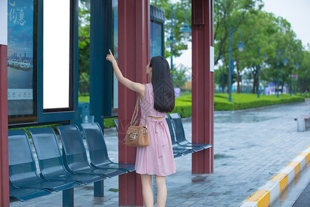 看公交站台指示牌的女性背景图片