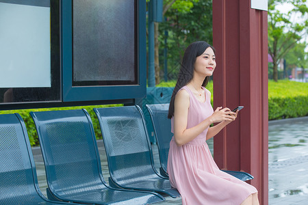 在公交车站台等待的青年女性背景图片