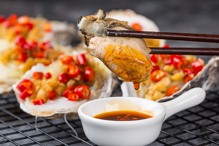 肥蚝筷子夹起肥美的生蚝肉蘸料背景