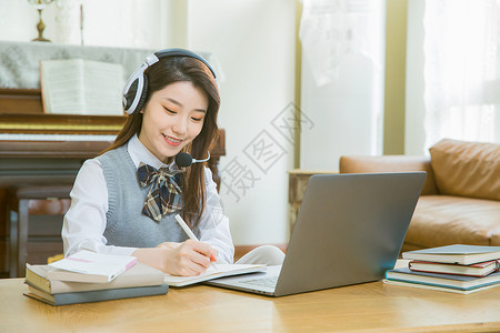 戴耳机的女学生上网课在线教育戴耳机的女学生上网课做笔记背景
